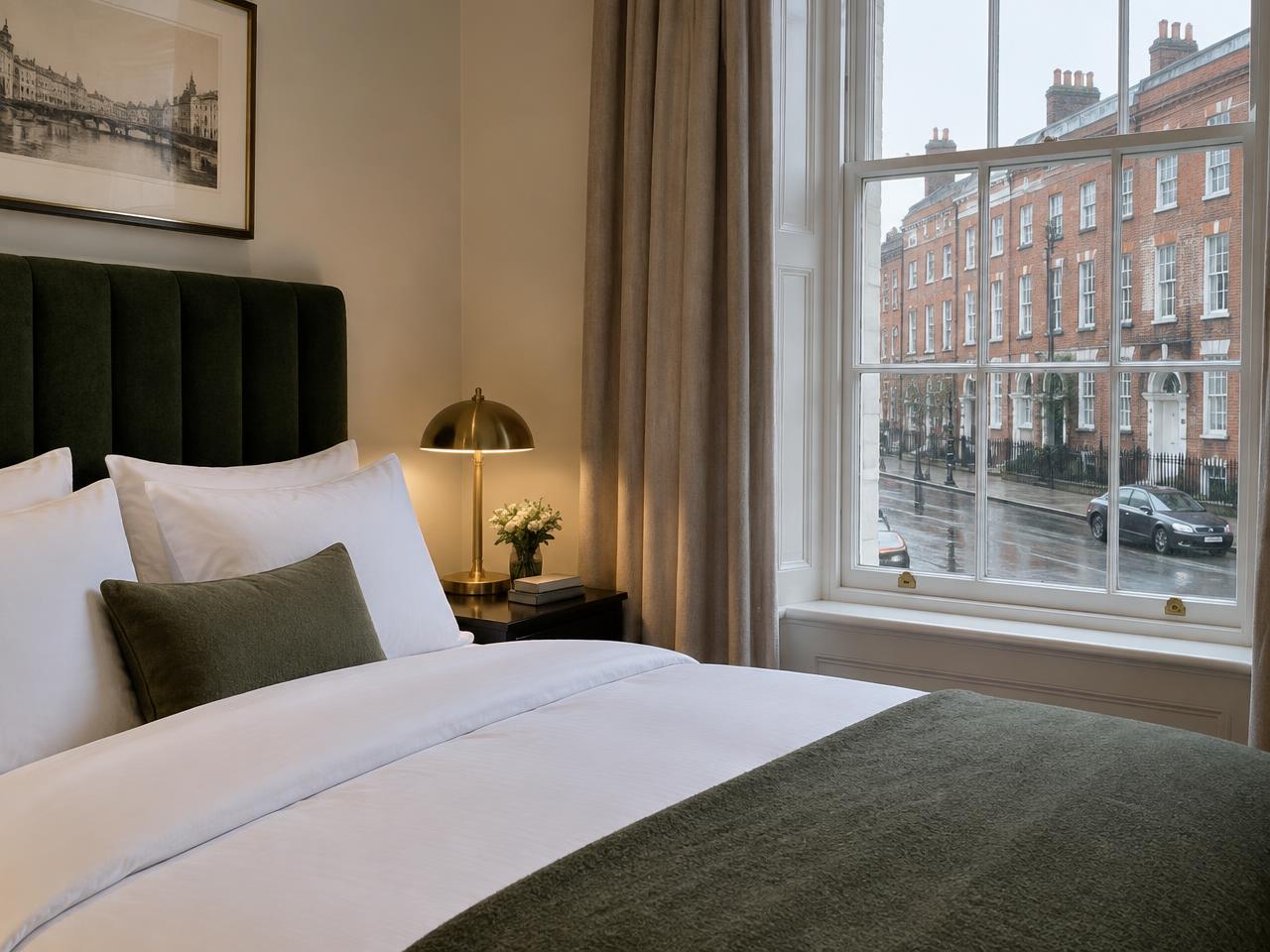 Serviced apartment bedroom with green headboard and brass lamps